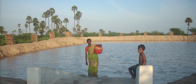 A woman and child taking water from an Ooranie in Southern India